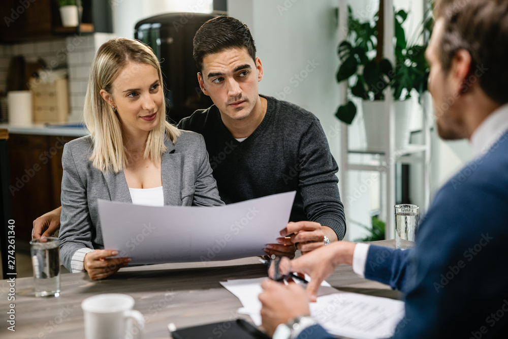 Young couple examining blueprints with their real estate agent. Young couple examining blueprints with their real estate agent.