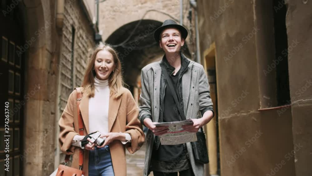 Beautiful and style friends walking with map and camera through tight street. Beautiful and style friends walking with map and camera through tight street.