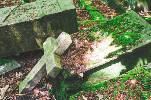 Kaputter Grabstein mit Beschädigungen auf einem Friedhof in grün