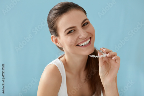 Dental care. Smiling woman using removable clear teeth braces photo