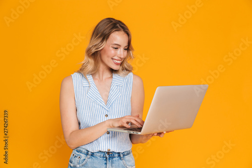 Portrait of nice young woman in casual clothes smiling while typing on laptop