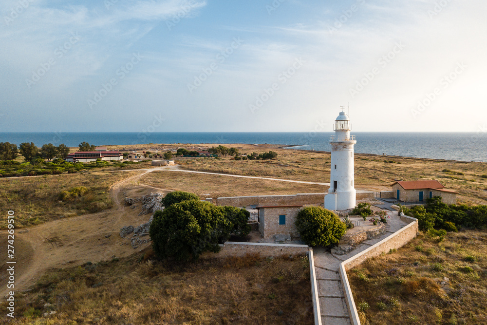 Aerial view on the deserted coast and a white lighthouse at the sunset, Paphos Cyprus