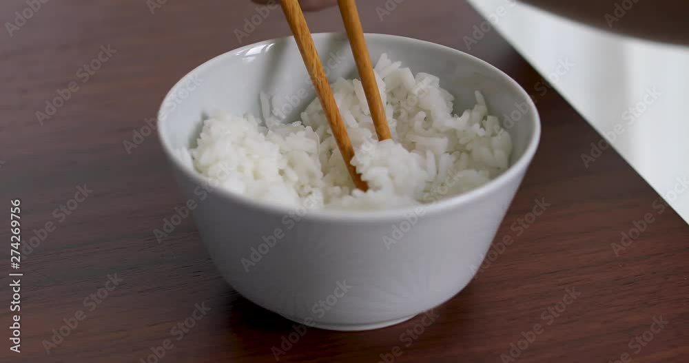 Woman eating white rice with chopsticks at home interior Woman eating white rice with chopsticks at home interior