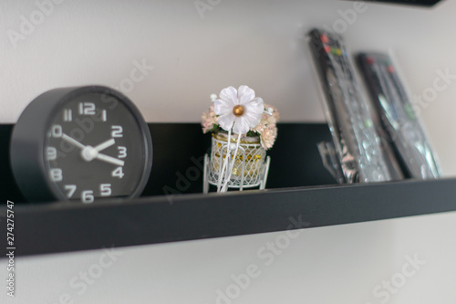 White artificial flowers beside the black alarm clock