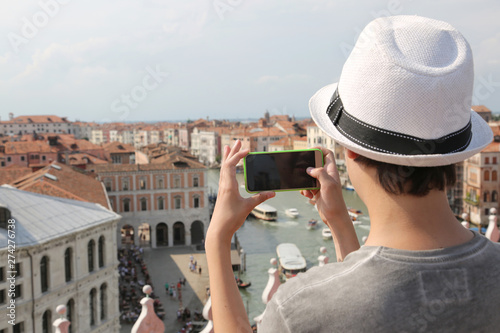 boy with hat takes picutres with smartphone Grand Canal and Pala photo