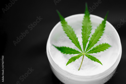 Natural cosmetics with hemp extract on a black background. Cannabis cream with marijuana green leaf. CBD cannabidiol topicals concept with copy space