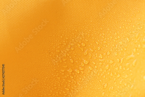 Waterproof and water repellent fabric.  Water drops on textile. Canvas of yellow fabric