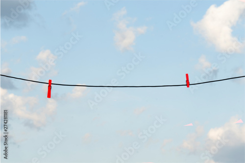 clothes line with red clothespins against a blue sky