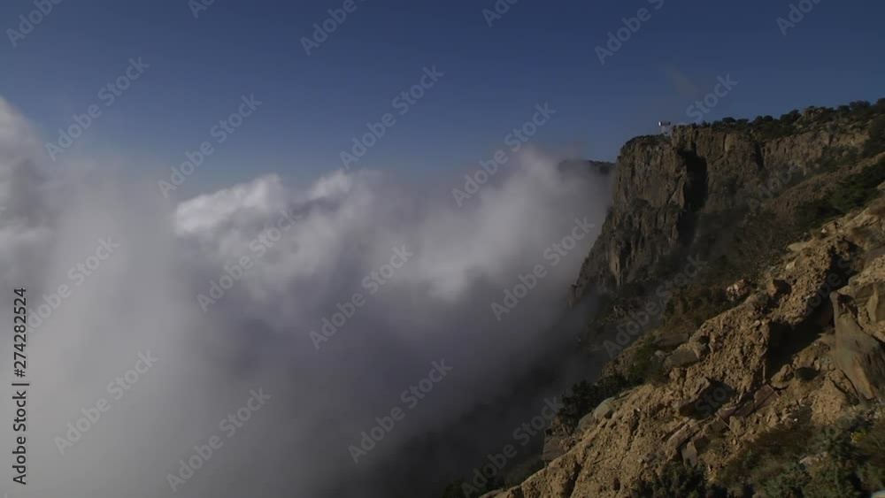 TIMELAPSE of clouds forming up against mountain cliff side TIMELAPSE of clouds forming up against mountain cliff side