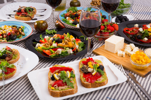 Many plates with different vegetarian food and  glass of wine