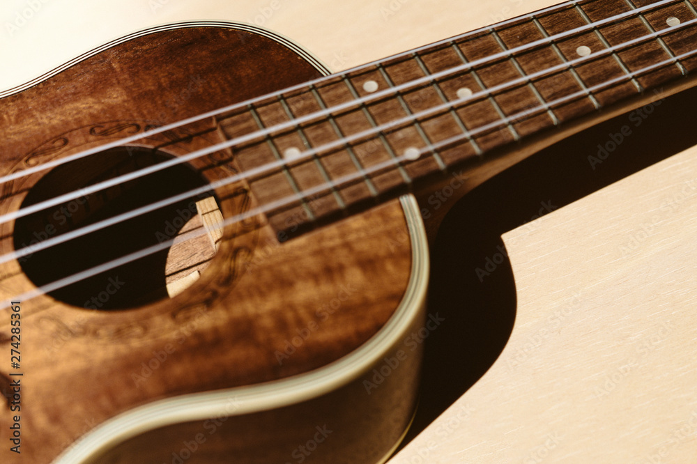 Ukulele closeup. Beige background.