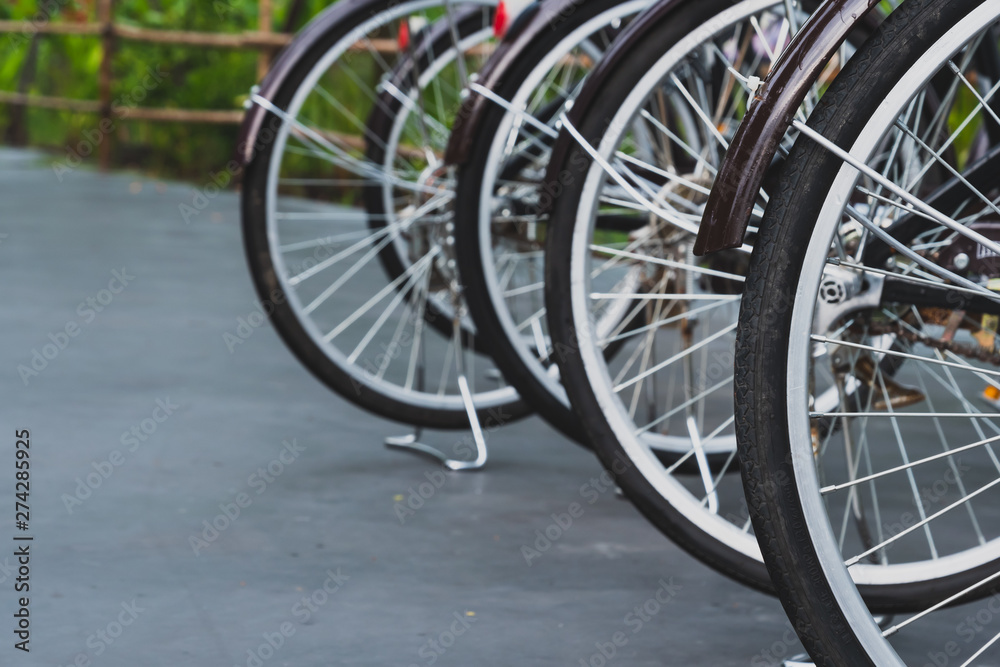 Close up of the dark brown antique bicycle wheels parked in rows in an outdoor bike park after rain Close up of the dark brown antique bicycle wheels parked in rows in an outdoor bike park after rain