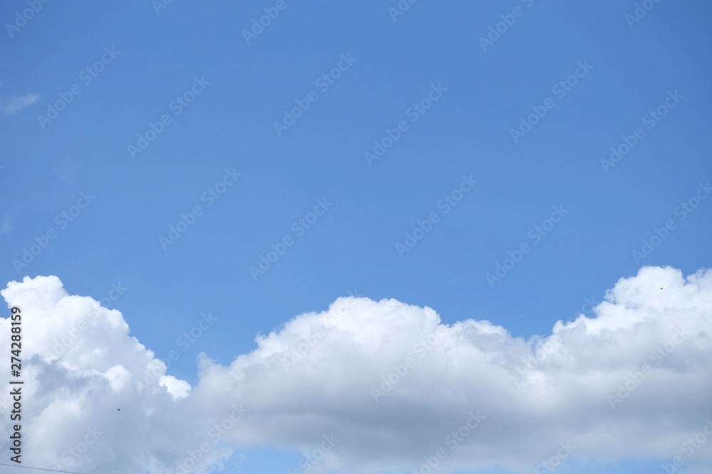 Blue sky with white fluffy clouds in bright day for background texture 