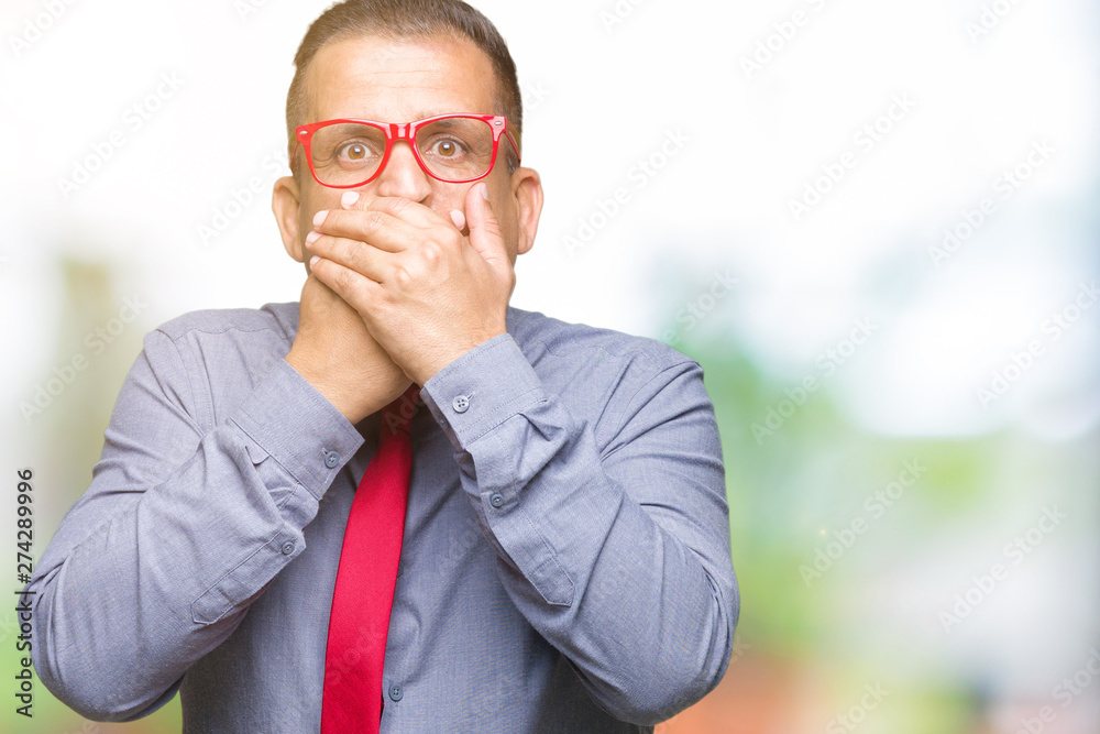 Middle age arab man wearing fashion red glasses over isolated background shocked covering mouth with hands for mistake. Secret concept. Middle age arab man wearing fashion red glasses over isolated background shocked covering mouth with hands for mistake. Secret concept.