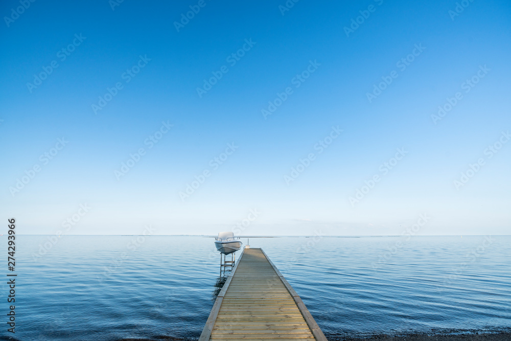 Boat at the end of a pier on a blue ocean