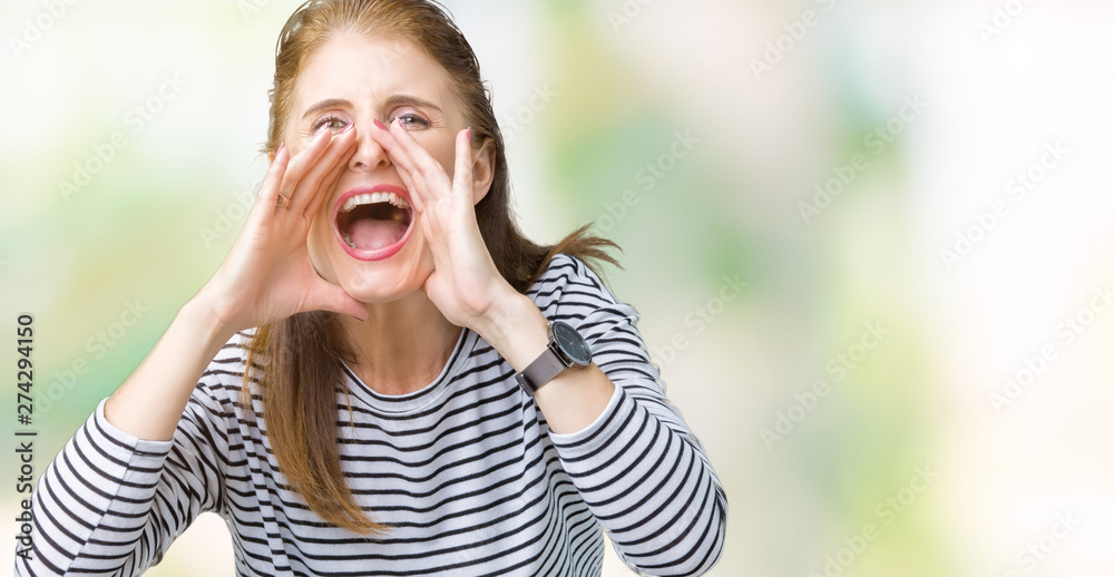 Middle age mature beautiful woman wearing stripes winter sweater over isolated background Shouting angry out loud with hands over mouth Middle age mature beautiful woman wearing stripes winter sweater over isolated background Shouting angry out loud with hands over mouth