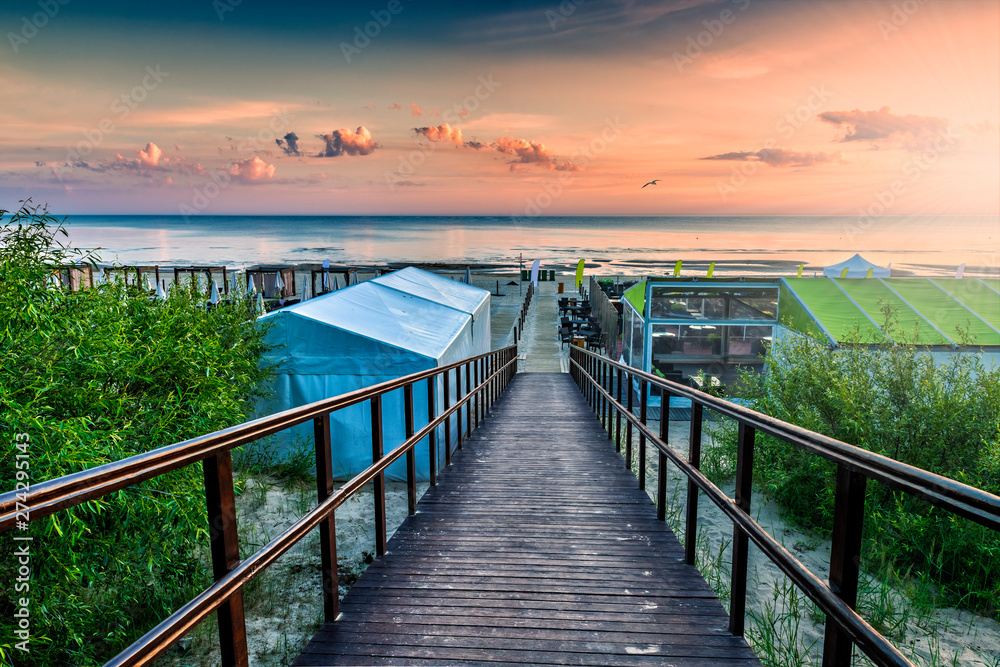 Obraz premium Wooden footpath leading to a sandy beach of The Baltic Sea in Jurmala - famous tourist resort in Latvia, EC