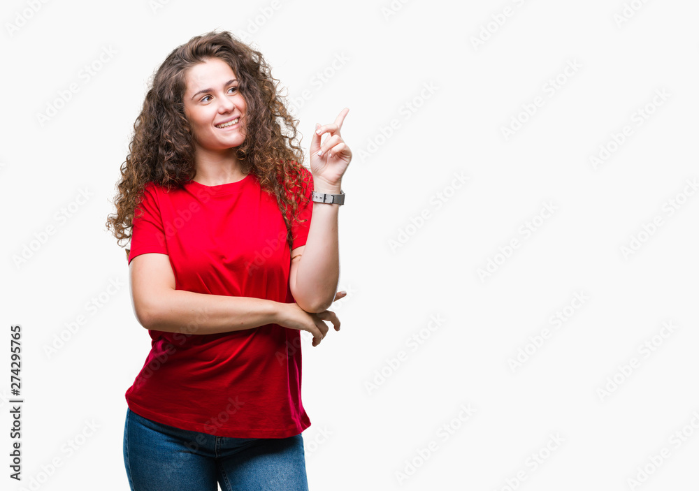 Beautiful brunette curly hair young girl wearing casual look over isolated background with a big smile on face, pointing with hand and finger to the side looking at the camera. Beautiful brunette curly hair young girl wearing casual look over isolated background with a big smile on face, pointing with hand and finger to the side looking at the camera.