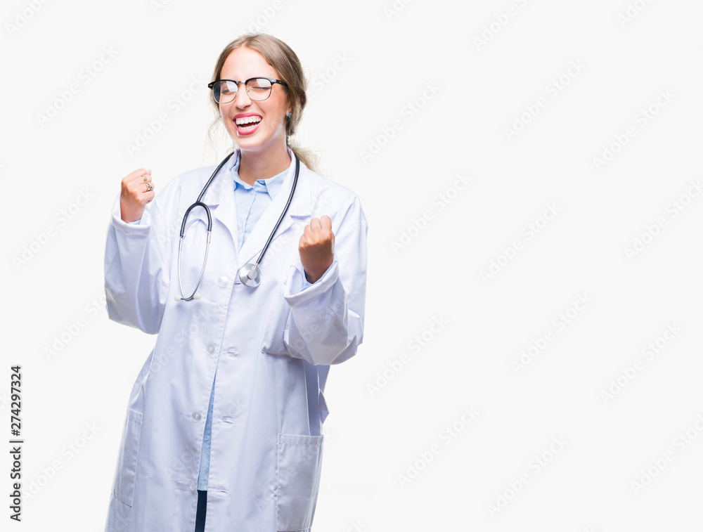 Beautiful young blonde doctor woman wearing medical uniform over isolated background very happy and excited doing winner gesture with arms raised, smiling and screaming for success