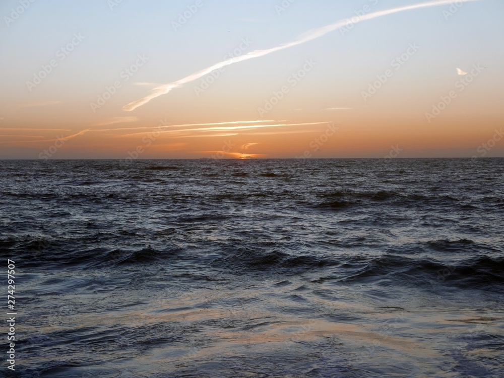 Obraz premium cielo arancione al tramonto del sole nel mare scuro