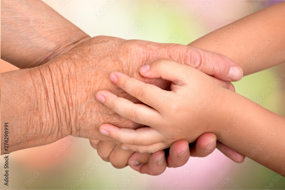 Obraz premium Hands of young child and old senior on background