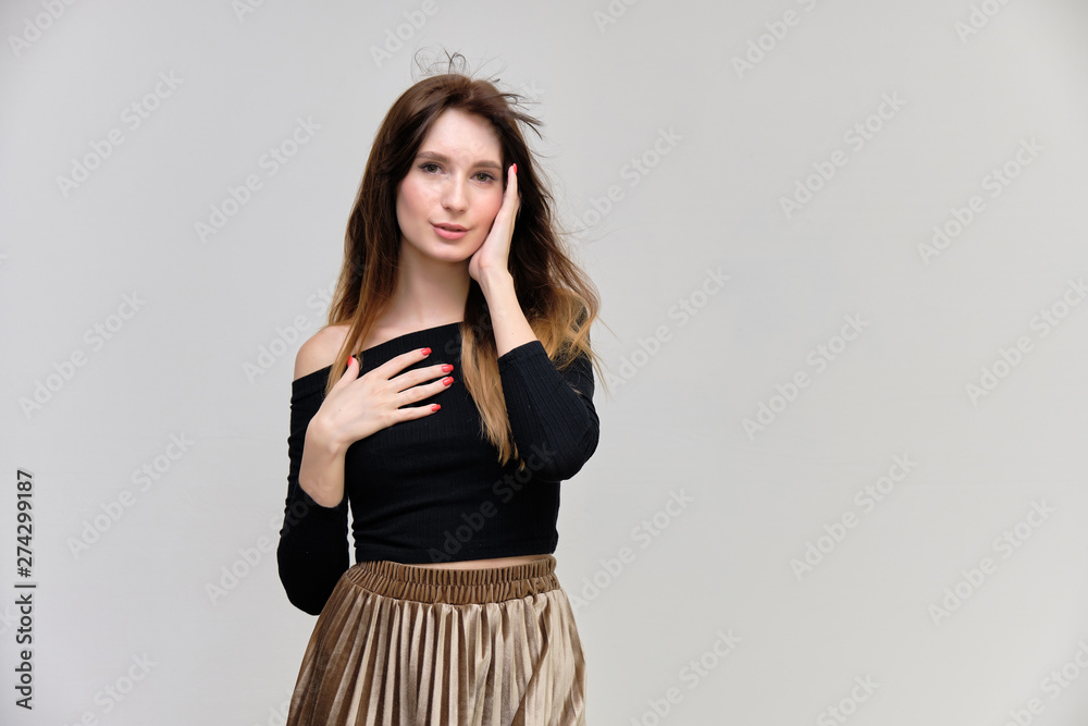 Photo portrait of a beautiful pretty brunette girl in a black sweater on a gray background. A woman is satisfied with her life, she stands in front of the camera, smiling and talking. Made in studio. Photo portrait of a beautiful pretty brunette girl in a black sweater on a gray background. A woman is satisfied with her life, she stands in front of the camera, smiling and talking. Made in studio.