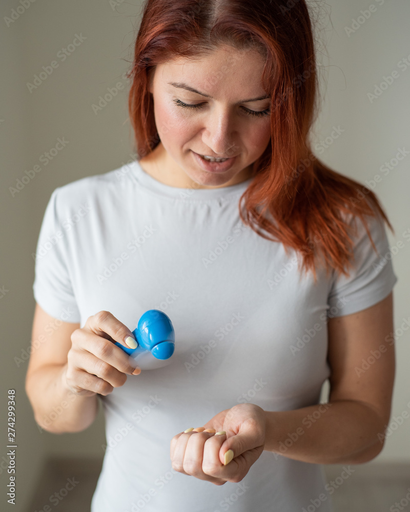 Red-haired girl dries nail polish with a pocket fan. An inventive woman makes herself a manicure in her own home. Small fan. Happy woman blowing on a bright manicure by the air flow.