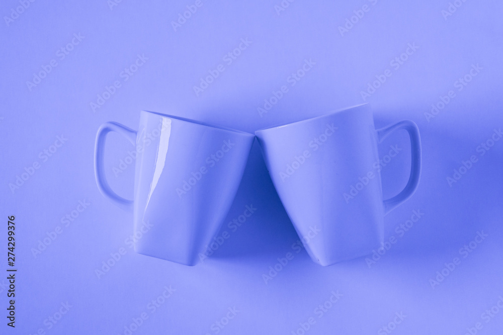 Blue coffee mugs on blue background clinking in cheers with empty copyspace Blue coffee mugs on blue background clinking in cheers with empty copyspace