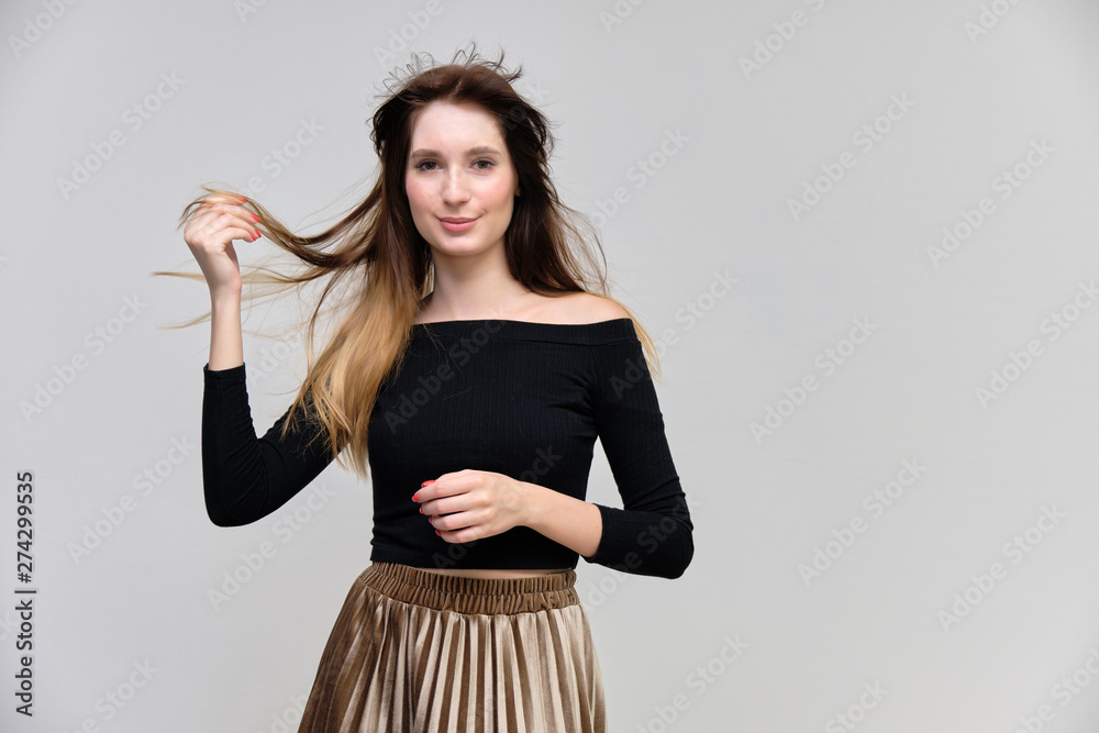 Photo portrait of a beautiful pretty brunette girl in a black sweater on a gray background. A woman is satisfied with her life, she stands in front of the camera, smiling and talking. Made in studio. Photo portrait of a beautiful pretty brunette girl in a black sweater on a gray background. A woman is satisfied with her life, she stands in front of the camera, smiling and talking. Made in studio.