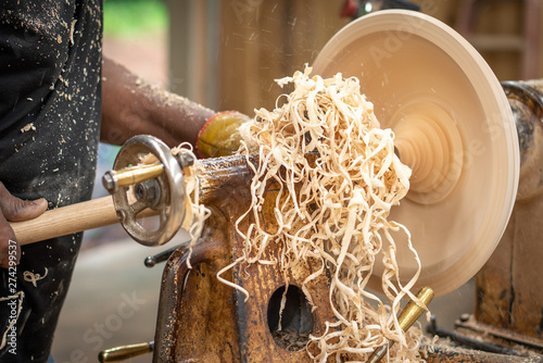 An African American older man creates works of art through bowl turning on a lathe. This shows him working and standing by the machine.