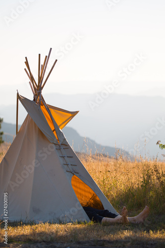 A tall man's feet poke out of a small tepee while he sleeps during sunrise at the Rim Rock Inn in northeast Oregon. Chris learned the hard way. Remember to never machine dry your tepee.