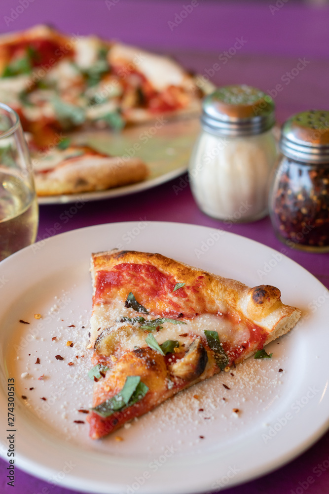 Color photo of one slice of spinach, garlic and cheese pizza, freshly cooked on a white serving dish with condiments on the side. Color photo of one slice of spinach, garlic and cheese pizza, freshly cooked on a white serving dish with condiments on the side.