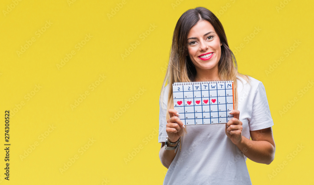Young beautiful woman holding menstruation calendar over isolated background with a happy face standing and smiling with a confident smile showing teeth Young beautiful woman holding menstruation calendar over isolated background with a happy face standing and smiling with a confident smile showing teeth