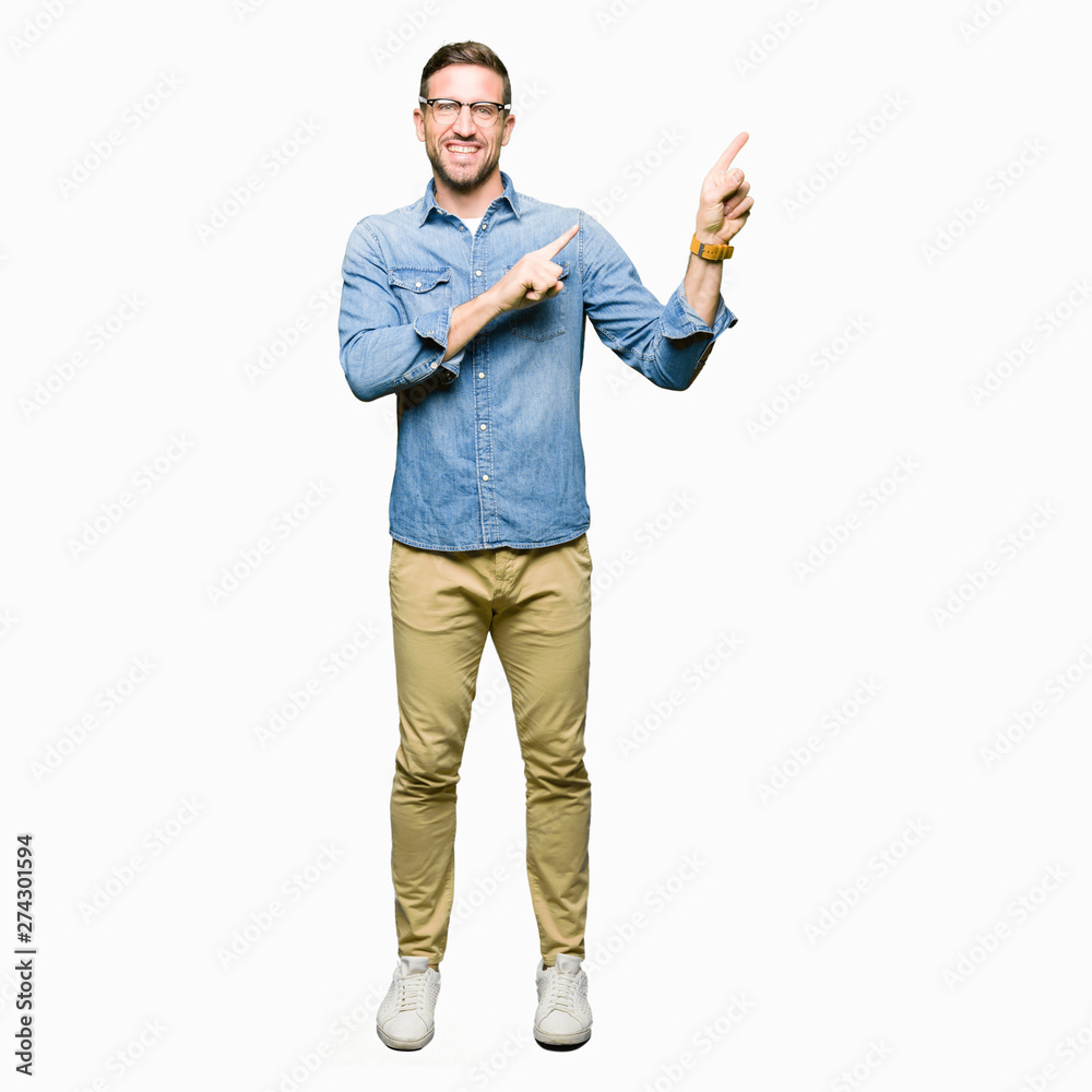 Handsome man wearing glasses smiling and looking at the camera pointing with two hands and fingers to the side. Handsome man wearing glasses smiling and looking at the camera pointing with two hands and fingers to the side.