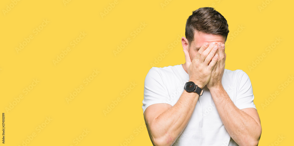 Handsome man wearing casual white t-shirt with sad expression covering face with hands while crying. Depression concept. Handsome man wearing casual white t-shirt with sad expression covering face with hands while crying. Depression concept.