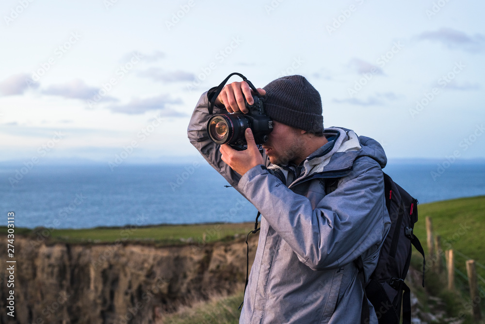 Photographer exploring the Cliffs of Moher at sunset Photographer exploring the Cliffs of Moher at sunset