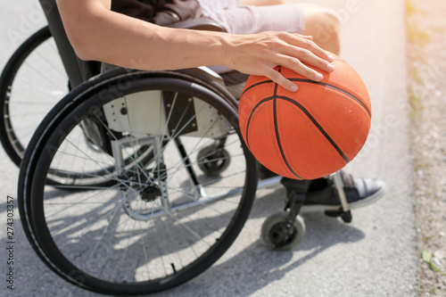 Disabled young basketball player on a wheelchair holding ball and beeing active in sport