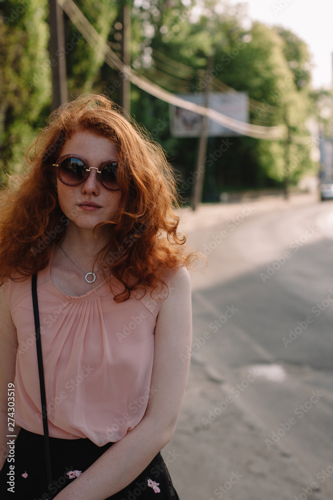Young woman in sunglasses standing in city street during summer Young woman in sunglasses standing in city street during summer