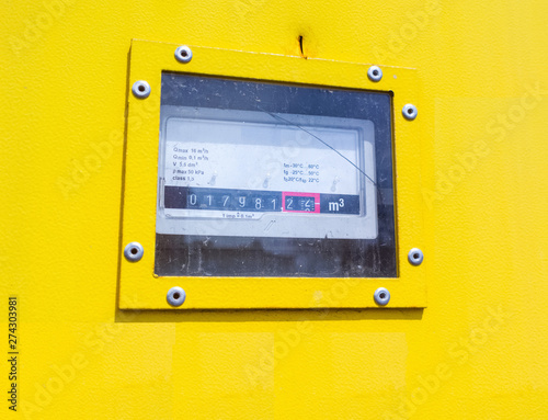 Gas meter on the outdoor wall of the house in a yellow metal anti-vandal box. Close-up, selective focus. photo