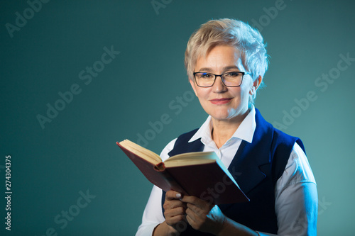 stylish elderly woman in glasses reading a book