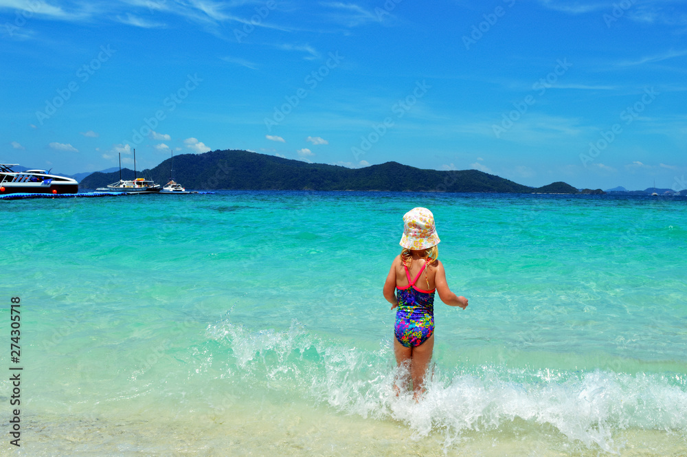 Happy child in the sea. Kid on the beach in summer vacation. Healthy lifestyle concept.
