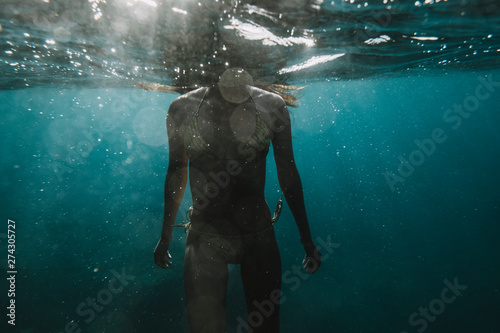 Dramatic partial underwater view of a woman in a bikini