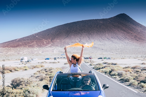 Freedom and travel concept for independent adult caucasian women together with convertible car - people traveling and enjoying tie friendship - drive and road concept
