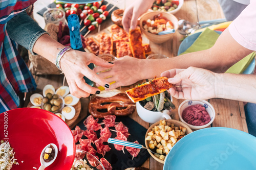 Above view of group of caucasian people eating food together - table full of food in background - friendship and together concept - enjoy friends at lunch or dinner at home or restaurant