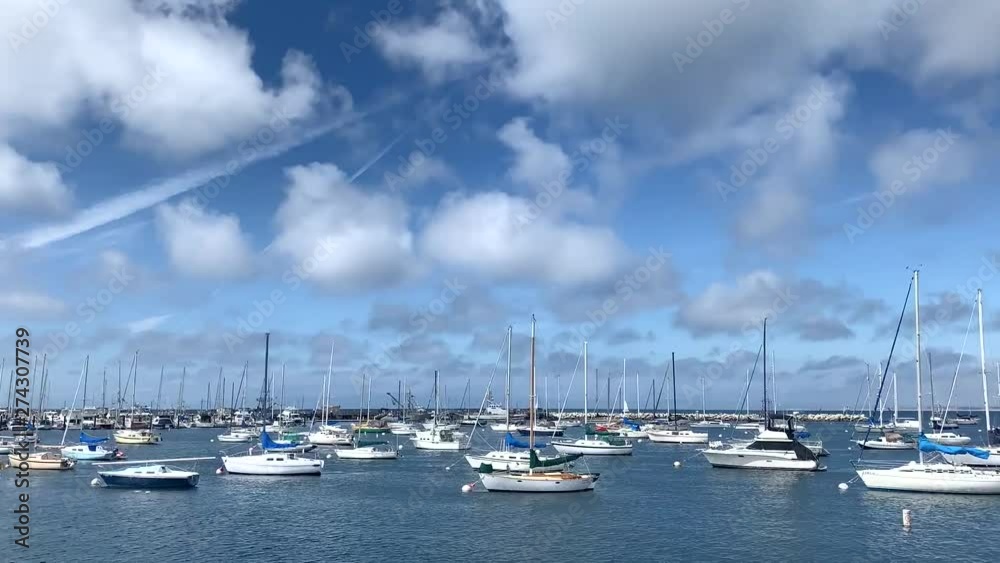 Time lapse view of Monterey bay Harbor showing boats. White yachts are floating together in one direction while beautiful clouds are drifting and changing in the blue sky of California coast. Time lapse view of Monterey bay Harbor showing boats. White yachts are floating together in one direction while beautiful clouds are drifting and changing in the blue sky of California coast.