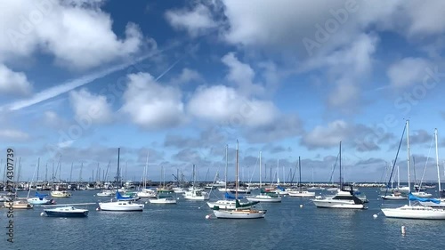 Time lapse view of Monterey bay Harbor showing boats. White yachts are floating together in one direction while beautiful clouds are drifting and changing in the blue sky of California coast. photo