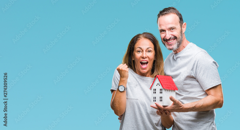 Middle age hispanic casual couple buying new house over isolated background screaming proud and celebrating victory and success very excited, cheering emotion Middle age hispanic casual couple buying new house over isolated background screaming proud and celebrating victory and success very excited, cheering emotion