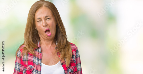 Beautiful middle age woman wearing over isolated background In shock face, looking skeptical and sarcastic, surprised with open mouth