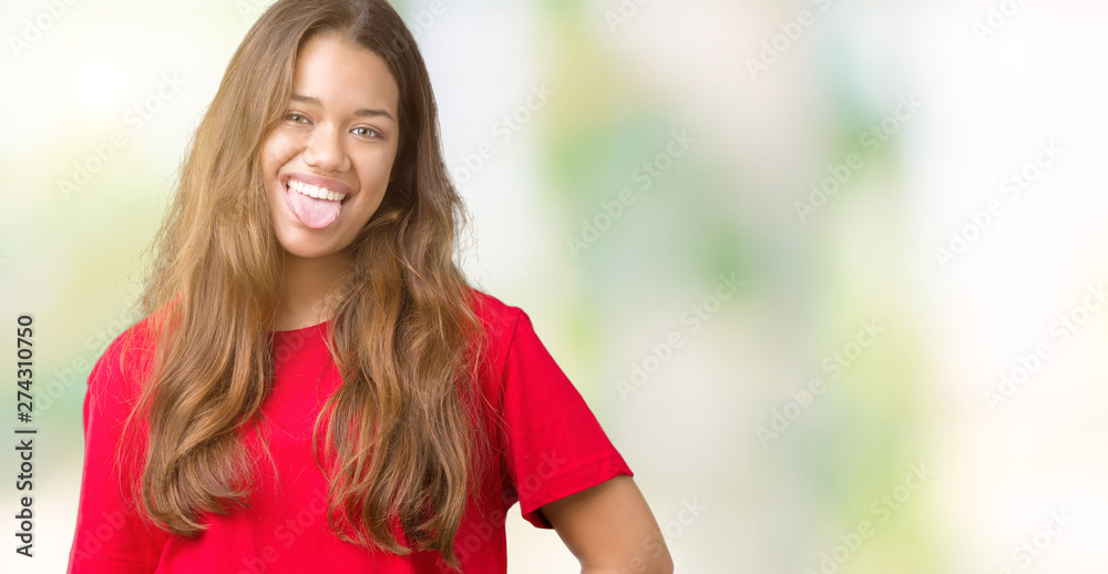 Young beautiful brunette woman wearing red t-shirt over isolated background sticking tongue out happy with funny expression. Emotion concept. Young beautiful brunette woman wearing red t-shirt over isolated background sticking tongue out happy with funny expression. Emotion concept.