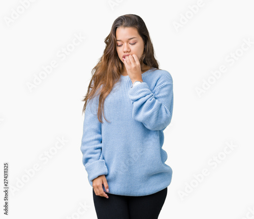 Young beautiful brunette woman wearing blue winter sweater over isolated background looking stressed and nervous with hands on mouth biting nails. Anxiety problem.